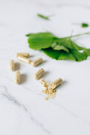 Doxwell Liver Detox Capsules – herbal capsules and herbs on marble surface